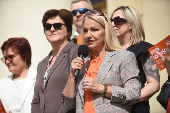 Kobieta z mikrofonem wygłaszająca przemówienie podczas wydarzenia z okazji Dnia Godności Osób z Niepełnosprawnością Intelektualną