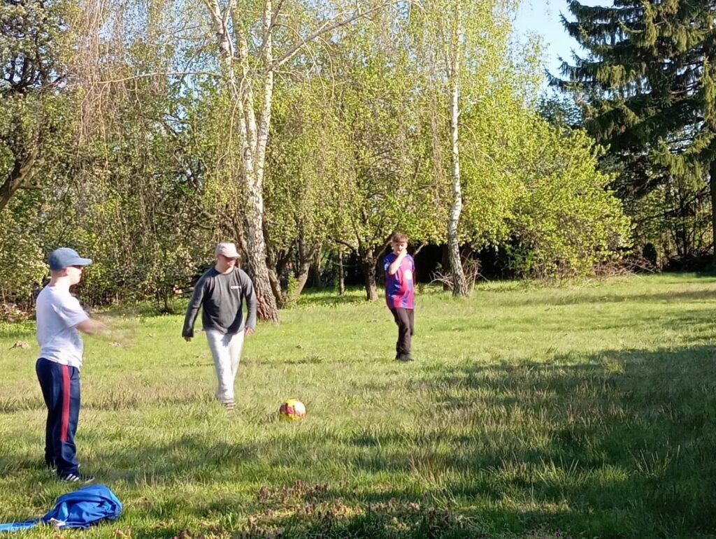Trzech uczestników domu treningowego grających w piłkę w ogrodzie podczas aktywności sportowej