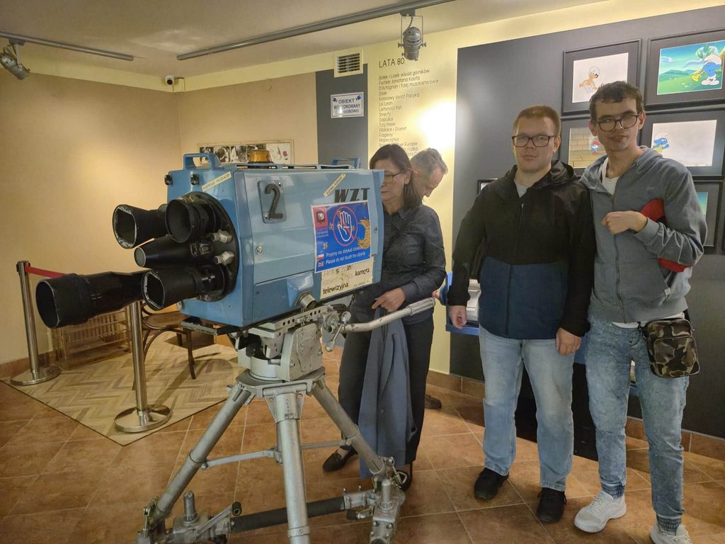 Uczestnicy wycieczki pozują przy zabytkowej kamerze telewizyjnej prezentowanej na ekspozycji w Muzeum Dobranocek w Rzeszowie.
