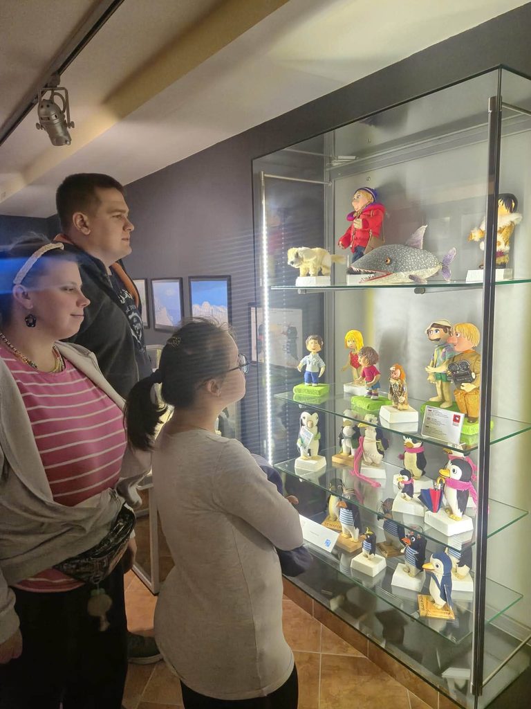 Uczestnicy wycieczki oglądają eksponaty w gablocie Muzeum Dobranocek w Rzeszowie. W szklanej witrynie znajdują się figurki bohaterów znanych bajek animowanych.